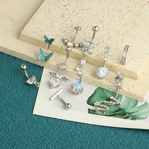 Macro shot of silver steel navel rings with zircon butterfly heart and snake charms