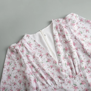 Dettaglio dello scollo a V con bottoni in tessuto e stampa floreale rosa su abito bianco