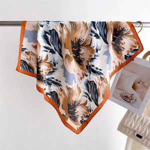 Detail of floral silk scarf with orange and blue flower print hanging in a lifestyle scene