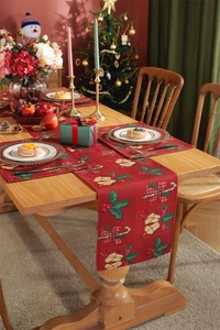 Close-up of red Christmas table runner with festive bells and holly prints on fabric