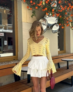 Detail of light yellow knit cardigan featuring hollow-out texture and flare sleeves