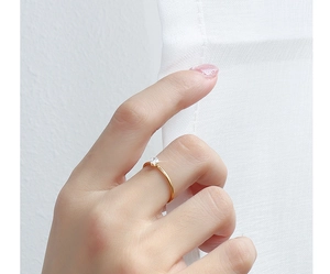 Close-up of minimalist 18k gold plated titanium ring with a single diamond on finger