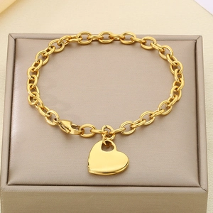 Detailed view of a gold heart pendant bracelet lying on a minimalist jewelry gift box
