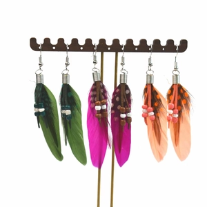 Three pairs of Bohemian feather tassel earrings with beads on a dark display stand