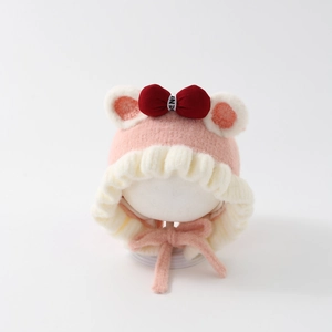 Close-up of pink knit baby hat with red velvet bow and soft plush earflaps detail