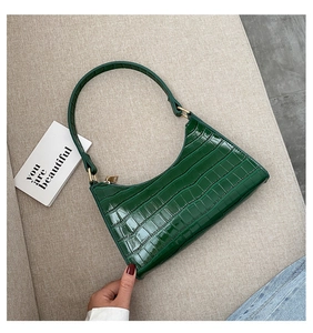 Detailed top view of dark green crocodile texture handbag with golden metal hardware detail