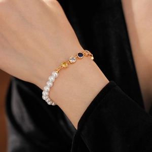 Detail eines Vintage-Herz-Edelstein- und Perlenarmbands am Handgelenk einer Frau