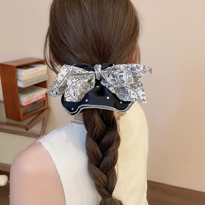 Détail d'un grand chouchou double couche à motifs paisley et pois sur une queue de cheval