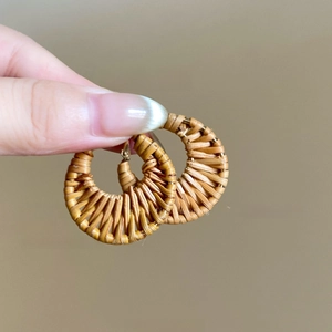 Close-up of handmade brown rattan woven C-shaped hoop earrings in bohemian style