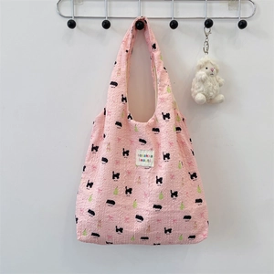 Pink quilted fabric shoulder bag with cat and pear patterns on a wall hook