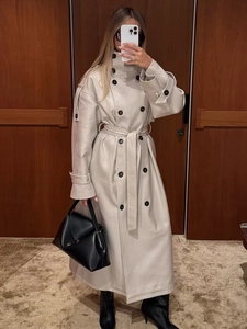 Close-up of beige leather trench coat with double-breasted black buttons and waist belt