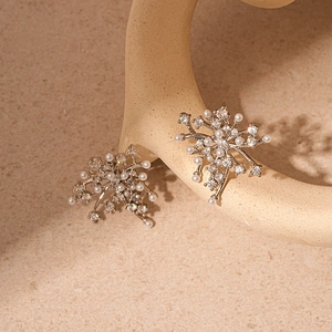 Macro view of silver floral earrings with zircons and pearls on a stone display