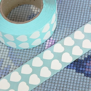 Macro shot of white heart-shaped DIY diamond painting stickers on light blue background