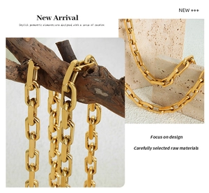 Close-up of a chunky gold Cuban chain necklace on a minimalist stone surface