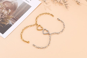 Detailed shot of hollow heart pendants on gold and silver chain bracelets with lobster clasp