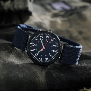 Detail of military quartz watch with blue nylon strap and luminous hands on camo fabric