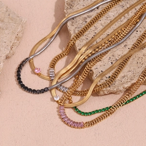 Close-up of gold and silver layered chains with colorful zircon stones on raw minerals