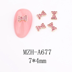 Detail of pink rhinestone bow nail art charm with gold alloy frame on a manicure model