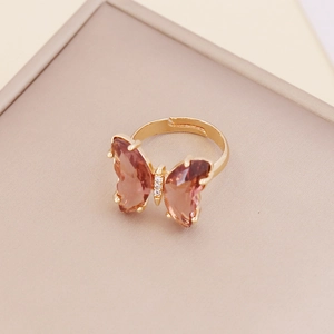 Detailed macro view of an adjustable gold butterfly ring with red gradient crystal wings