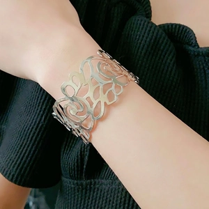 Silver hollow wide open bangle bracelet featuring intricate cutout curved patterns