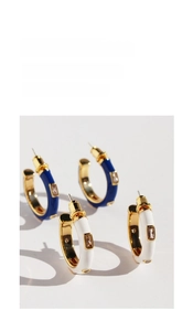 Detail of C-shaped gold-plated hoop earrings with blue and white enamel and zircon