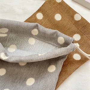 Macro detail of corduroy drawstring pouches with polka dot patterns and cotton ropes