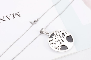 Detail of silver stainless steel tree of life pendant with fine chain on white background