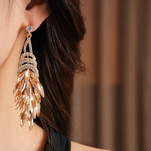 Gros plan de boucles d'oreilles vintage dorées à glands et strass champagne sur un modèle
