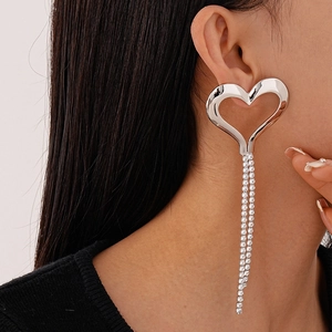 Macro detail of large silver heart earrings with sparkling long rhinestone tassels