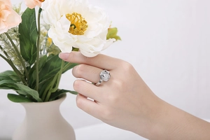 Close-up of a silver stainless steel ring with a 3D white camellia flower on a hand