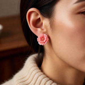 Detailed close-up of pink layered resin flower earrings with gold pistil accents on a model
