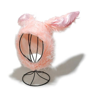 Detailed view of pink plush bunny hat with long ears and satin lining on a stand