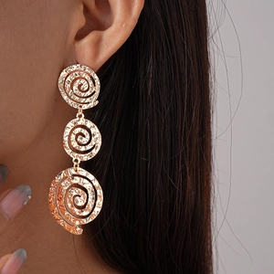 Gros plan sur des boucles d'oreilles dorées à trois disques spiraux ajourés avec texture
