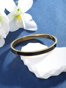 Detail of minimalist gold and black oval cuff bracelet on elegant stone stand