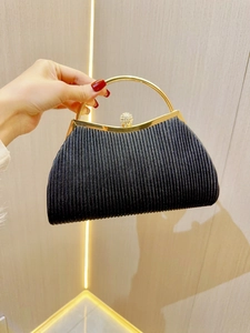 Detail of elegant black pleated evening clutch bag with gold ring handle and diamond clasp