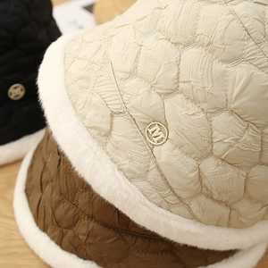 Close-up of quilted winter bucket hats with plush faux fur trim and metal M detail
