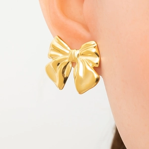 Close-up of 18k gold plated stainless steel bow earrings worn by a model in natural light