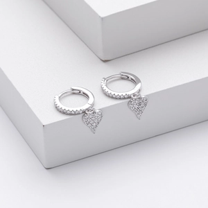 Close-up of polished silver heart hoop earrings with sparkling cubic zirconia stones