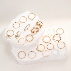 Detail of 21-piece gold ring set featuring butterfly, pearls, and crystals on stone blocks