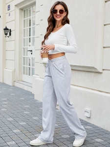 Pantaloni svasati a vita bassa grigio chiaro da donna con top corto bianco alla moda