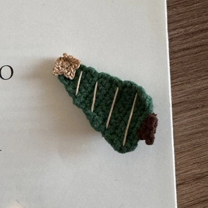 Close-up of a handmade crochet Christmas tree hair clip with a star on open book pages