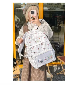 Detail of white school backpack featuring dog patterns and badges in a transparent pocket