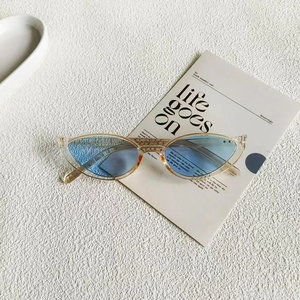 Fashionable cat-eye sunglasses with champagne frame and blue lenses on a minimal card