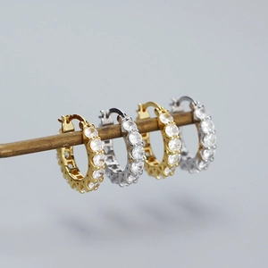 Détails macro des boucles d'oreilles créoles dorées et argentées pavées de zircons