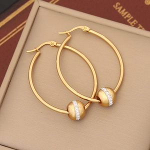 Close-up of golden hoop earrings featuring a sparkling rhinestone sphere on leather