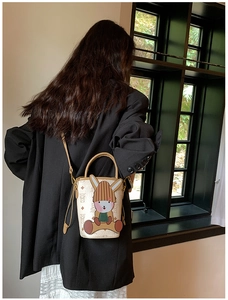 Close-up of stylish beige bucket bag with cute rabbit motif and brown leather trim