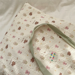 Close-up of seersucker tote bag featuring cute cartoon bear pattern and woven label