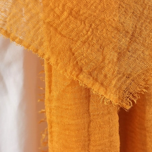 Detailed macro view of the yellow-orange crinkled cotton linen scarf with frayed edges