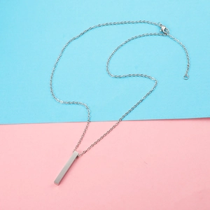 Minimalist silver stainless steel bar necklace on a vibrant blue and pink background