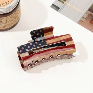 Detail shot of large acetate claw clip with American flag pattern on a neutral desk